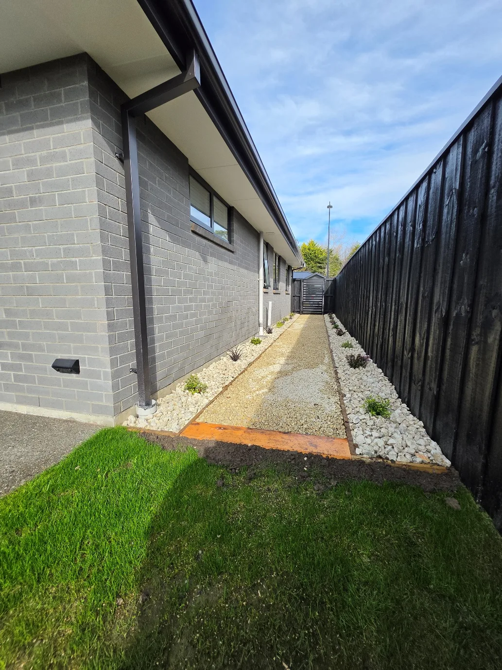 Decorative gravel side path with black timber fencing at 25 Derbridge Street landscaping project